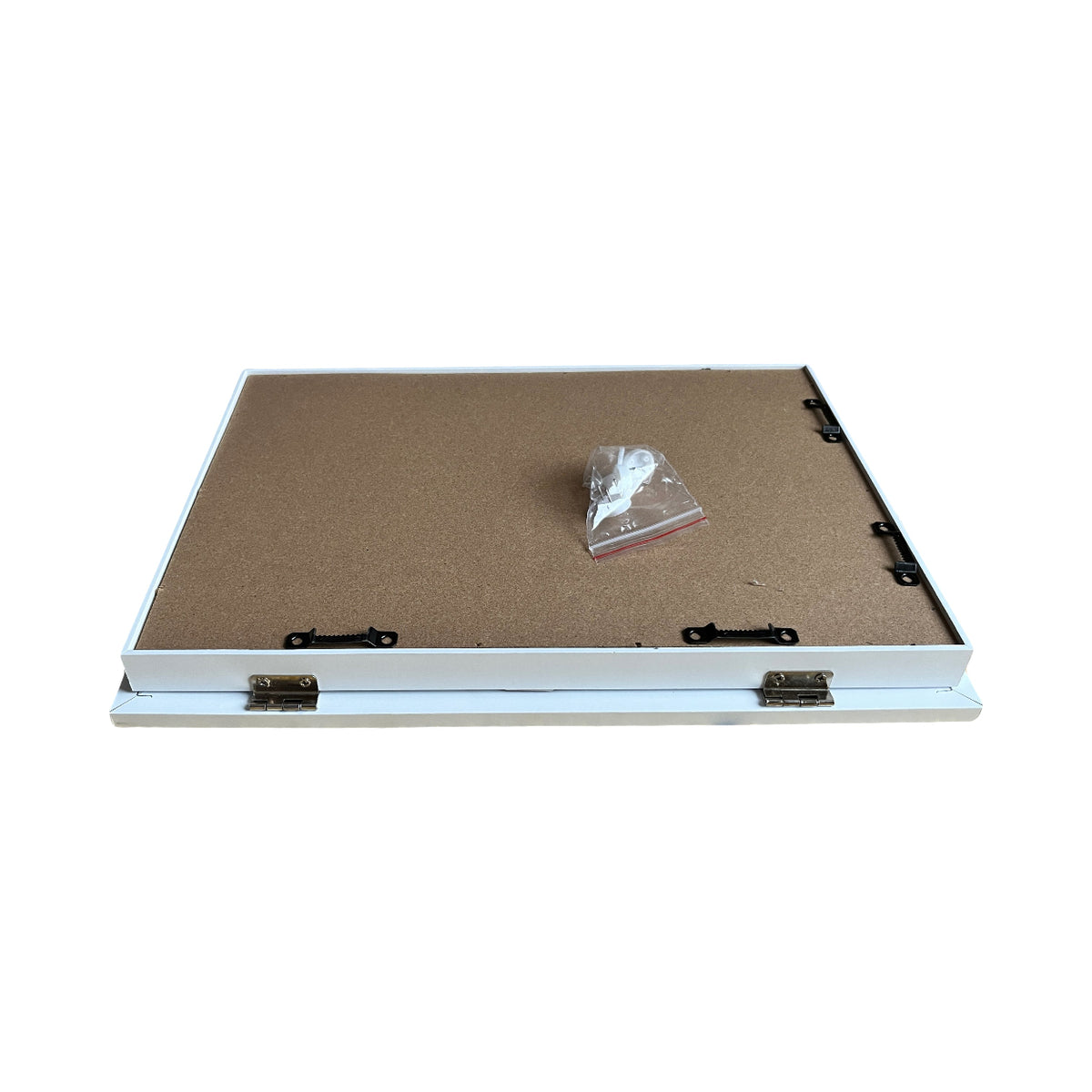 Brown board with a white frame and a small clear bag with fixings in, lying on a white background