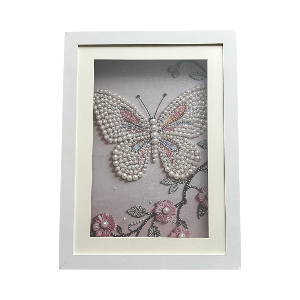 Framed butterfly artwork with pearl embellishments on a light background