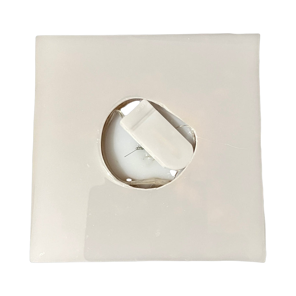 Christmas Tree Pyramid Lamp - Bottom view of a square, off-white translucent resin tile with a circular cut-out in the centre, showing a white backing insert of micro lights battery casing.
