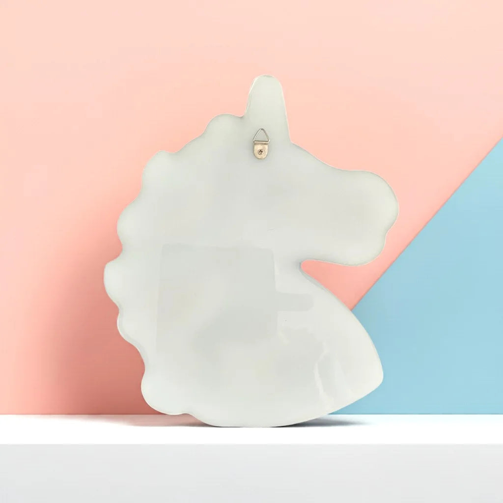 White back of a Unicorn-shaped decal on a pastel pink and blue background