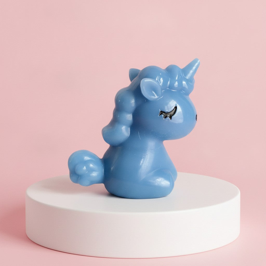 A light blue unicorn figurine sitting on a white cylindrical pedestal against a solid pink background.