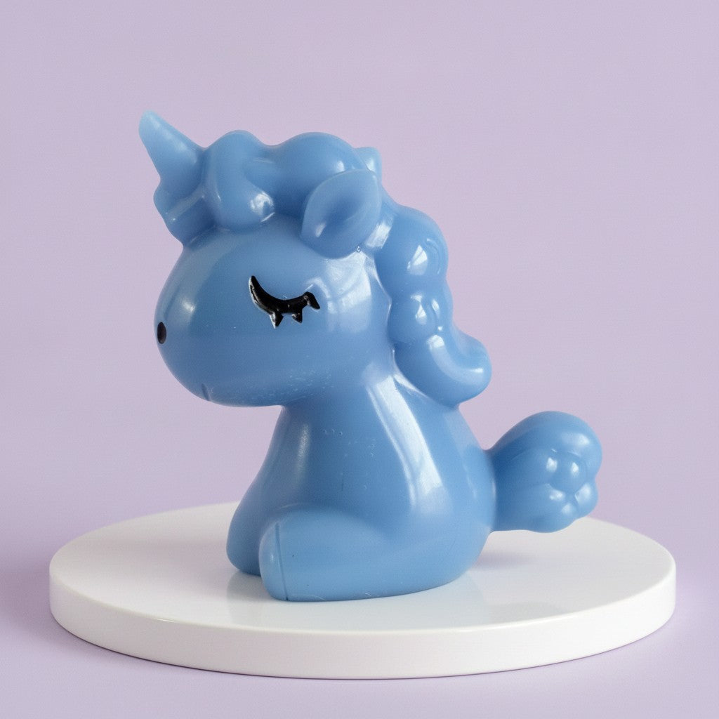 A light blue glossy unicorn figurine with closed eyes, sitting on a round white platform against a soft lavender background.