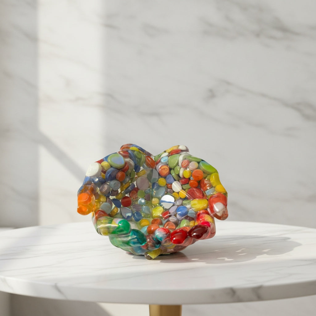 Colorful resin cupped hands sculpture on a marble surface with a marble backgrounds  