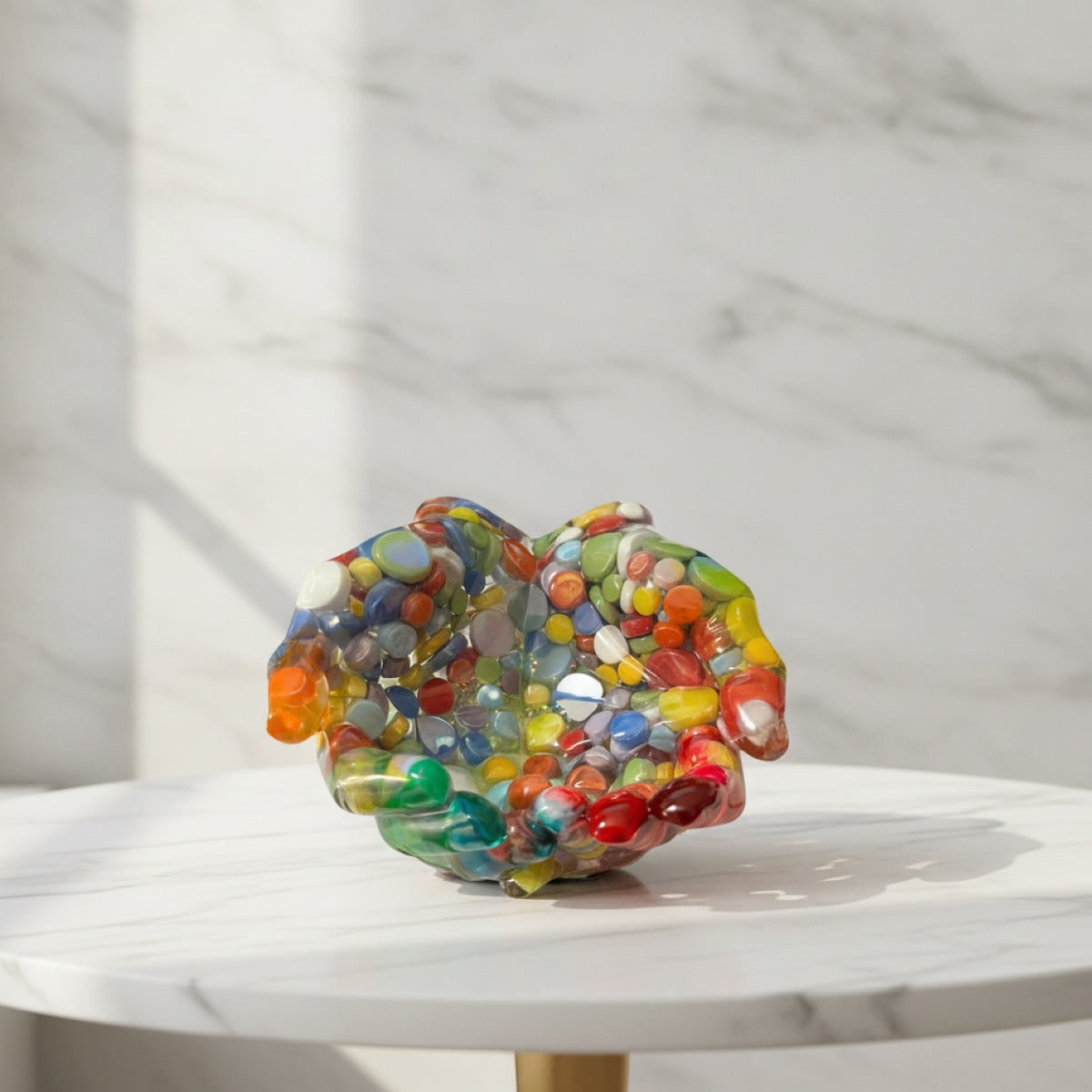 Colorful resin cupped hands sculpture on a marble surface with a marble backgrounds  