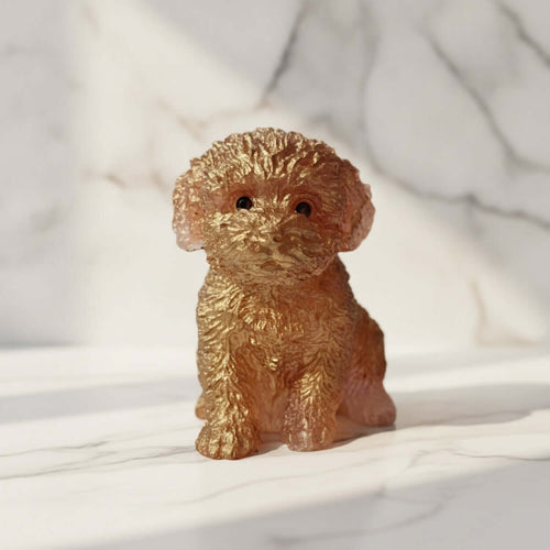 A small translucent amber-brown figurine shaped like a curly-haired puppy, sitting on a white marble surface with a matching marble background.