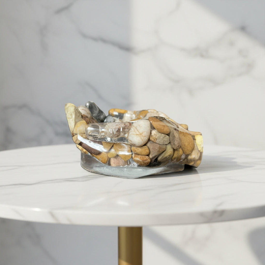 Decorative resin hands bowl with stones and crystals on a marble surface