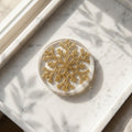 Christmas Snowflake Coaster - A round clear resin coaster featuring a glittery gold snowflake design, resting on a white marble tray with soft leaf shadows.