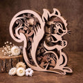 Wooden Squirrel Ornament - A laser-cut wooden squirrel figurine with intricate cut-out details, displayed on a rustic wooden surface with small white flowers and a log slice prop against a warm brown background.