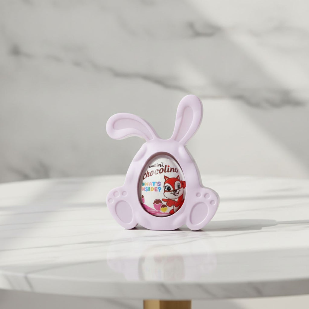 A light purple bunny-shaped chocolate holder displaying a Chocolino chocolate egg, set on a white marble table with a matching marble background.