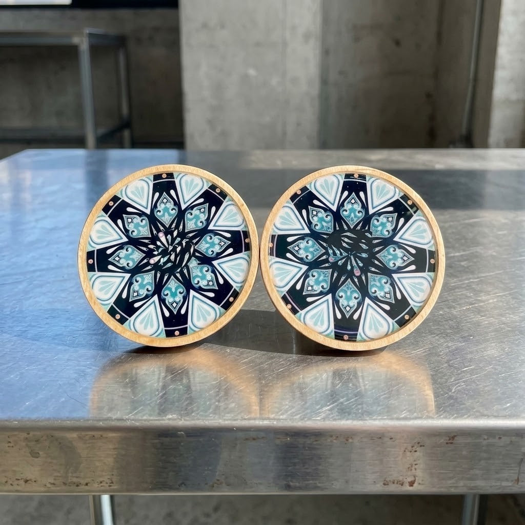 Mandala Bamboo Coasters - Two round coasters with a light wood rim and a black, white, and blue mandala pattern, displayed on a brushed silver surface 