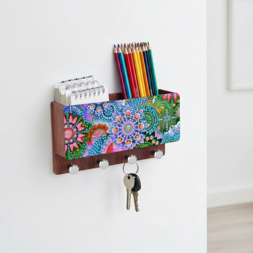 Storage Rack Box organizer with a colorful mandala-patterned front panel, dark wood sides, three silver hooks holding keys, and a top slot holding notebooks and colored pencils, shown mounted on a white wall.